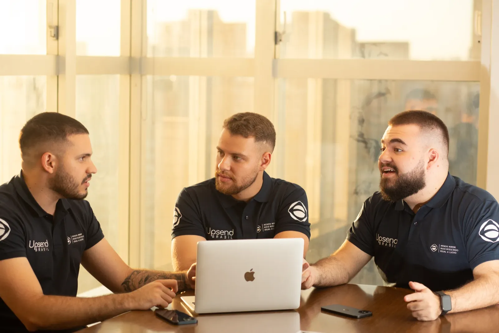 Equipe da Upsend Brasil trabalhando à mesa com notebooks